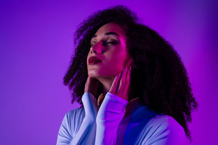 Portrait of a fashionable young woman with curly hair, neon lighting accentuating a trendy style in ultraviolet huesの写真素材