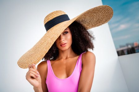 Stylish woman in a chic outfit wearing a wide brimmed straw hat during a sunny photoshoot on a...