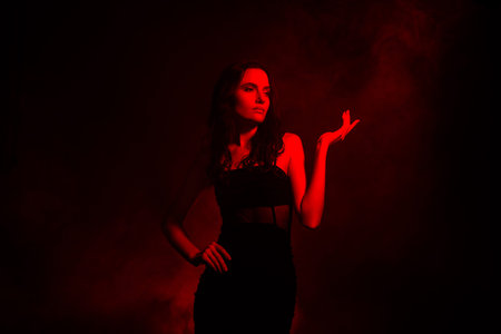 Stylish brunette woman posing in artistic red illuminated background with a glamorous expression