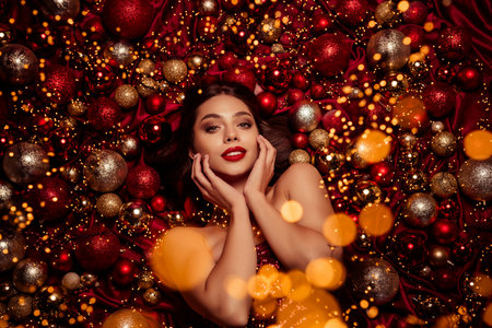 Gorgeous festive portrait of a stylish model lying among Christmas decorations with warm lights magical holiday moodの写真素材