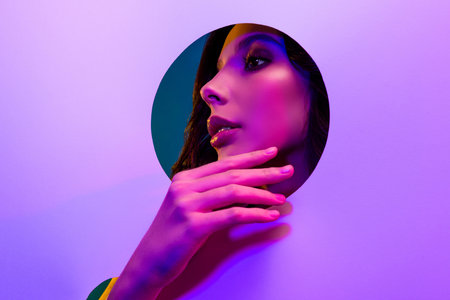 Elegant young woman posing with vibrant neon light background showcasing beauty and eleganceの写真素材