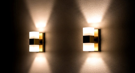 Two lamps on the wall in a dark room illuminated by spotlightsの素材