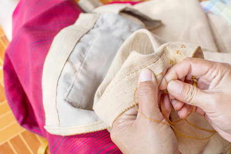 old woman's hand to picth brown yarn in to clothes by needle