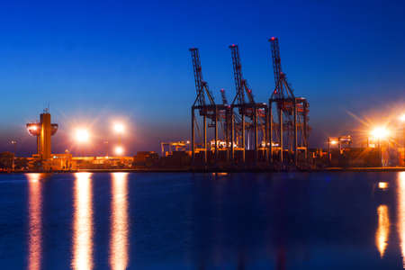 Container Cargo freight ship with working crane bridge in shipyard at dusk for Logistic Import Export backgroundの写真素材