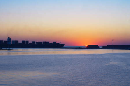 Container Cargo freight ship with working crane bridge in shipyard at dusk for Logistic Import Export backgroundの写真素材