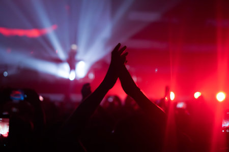 silhouettes of concert crowd in front of bright stage lightsの写真素材