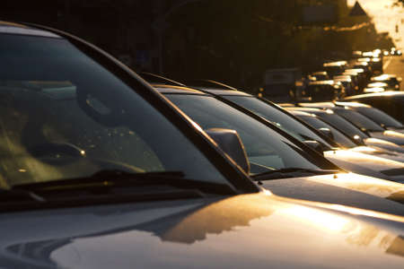 Several cars parked in a parking lot against sun riseの写真素材