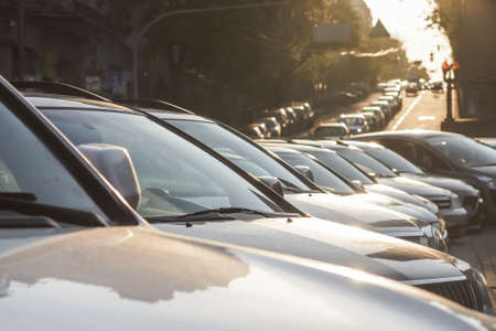 Several cars parked in a parking lot against sun riseの写真素材