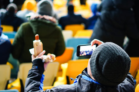 A boy on a stadium soccer field, in the winter photographs a hot dogの写真素材