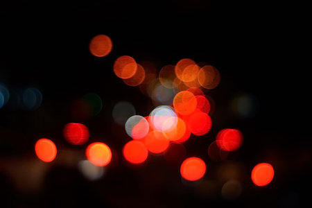Bright circles from streetlamps on defocused photo of night street.