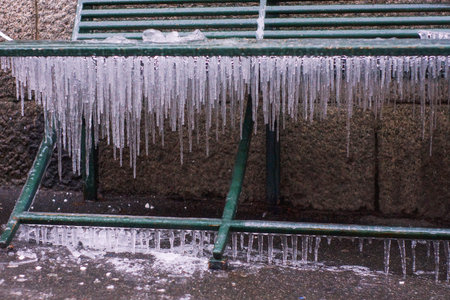 outdoor metal bench, all covered with ice and icicles