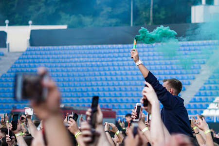 Audience with hands raised at a music festival and lights streaming down from above the stage. Soft focus, high ISO, grainy image.の写真素材