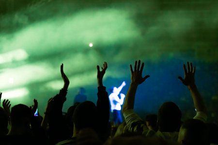 Crowd at a music concert, audience raising hands up