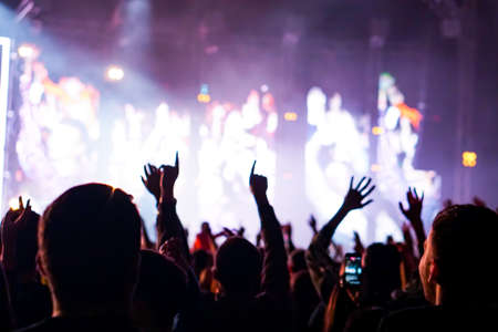 crowd cheering and hands raised at a live music concertの写真素材