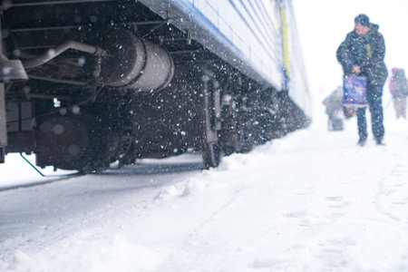 Woman with luggage is boarding to train on railroad station during snowing