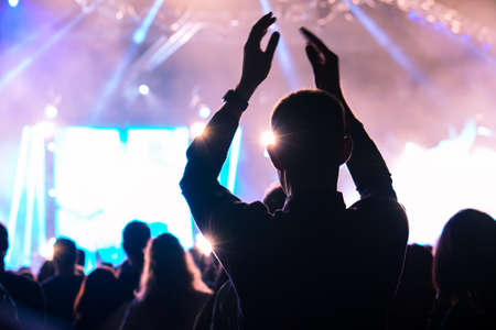 crowd cheering and hands raised at a live music concertの写真素材