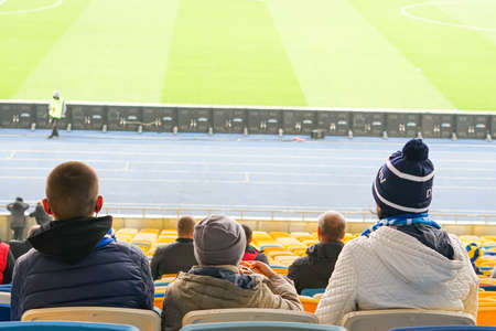 Parents and children watching while enjoying a game from seats for spectators at the stadiumの写真素材