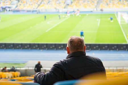 spectators watch football in a half-empty stadiumの写真素材