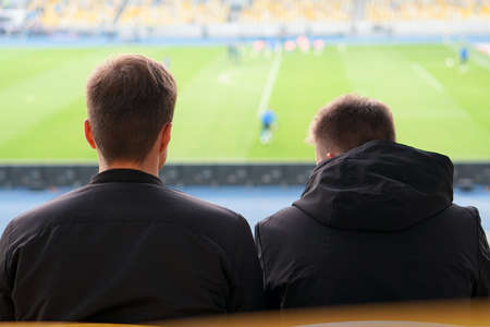 spectators watch football in a half-empty stadiumの写真素材