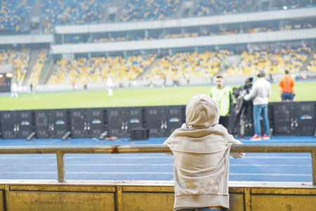 Youn white boy watchin football game at stadium