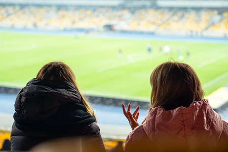 spectators watch football in a half-empty stadiumの写真素材