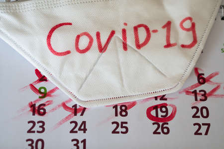 the respirator lies on calendar with marks. Concept of the raging coronavirus pandemic in 2020の写真素材