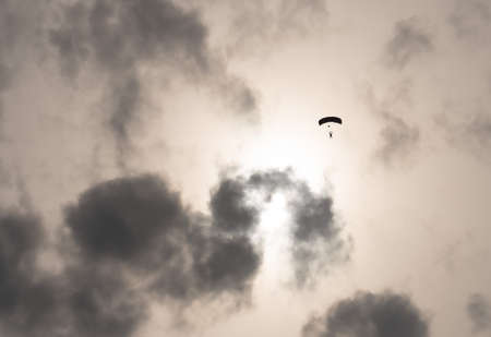 Silhouette of a parachutist in flight before sunsetの写真素材