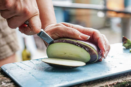 the girl cuts the eggplant on the street, and in the summer kitchenの写真素材