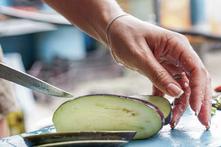 the girl cuts the eggplant on the street, and in the summer kitchenの写真素材