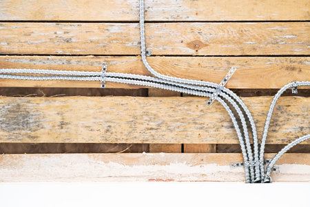 Aluminum tubing for wire protection lined up on old concrete wall.