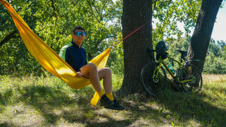 cyclist rests on a hammock, yellow hammock and open airの写真素材