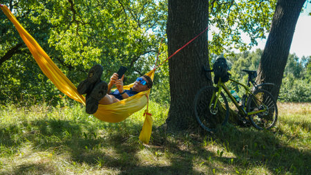 cyclist rests on a hammock, yellow hammock and open airの写真素材