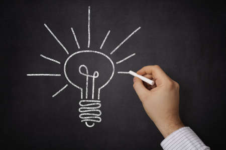 Businessman sketching a light bulb on a glassの写真素材