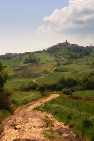 An Italian landscape with an old road in the hills that goes to a small townの写真素材