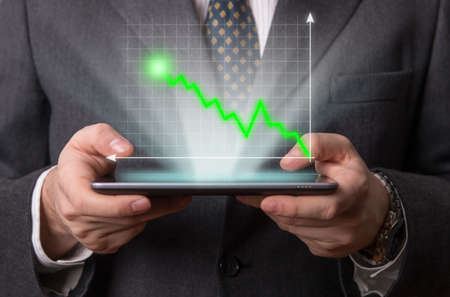 Businessman using a futuristic tablet with an holography diagramの写真素材