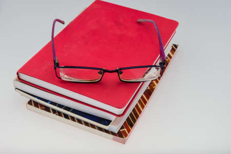 stack of books with a pair of eyeglasses on topの写真素材