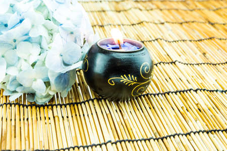 Branch of light blue hydrangea flower with candle  on bamboo blind backgroundの写真素材