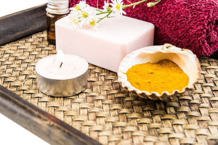 Spa concept with aromatic essence,soap and turmeric powder on tray decorated by cutter flower and lit tea candle decorated by cutter flower and lit tea candleの写真素材