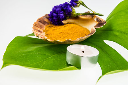 Spa set concept with turmeric powder in seashell decorated with purple statice flower  and green leafの写真素材