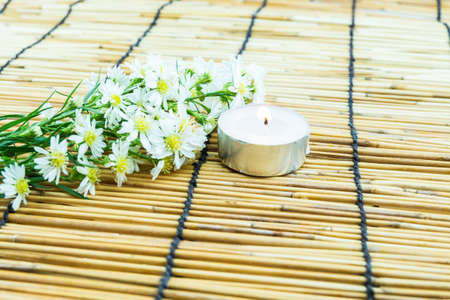 White cutter flower and tea light candle on bamboo backgroundの写真素材