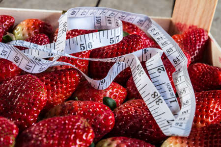 strawberry with Measure tape on old wooden backgroundの写真素材