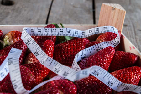 strawberry with Measure tape on old wooden backgroundの写真素材