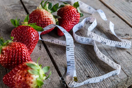 strawberry with Measure tape on old wooden backgroundの写真素材
