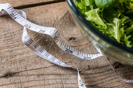 Salad in glass with measuring tape on wood backgroundの写真素材