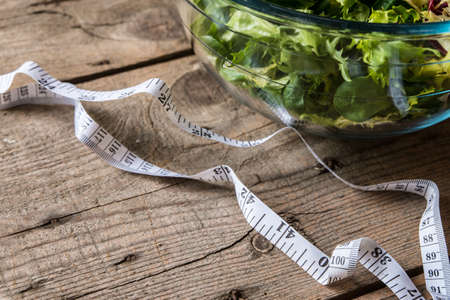 Salad in glass with measuring tape on wood backgroundの写真素材