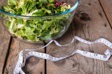 Salad in glass with measuring tape on wood backgroundの写真素材