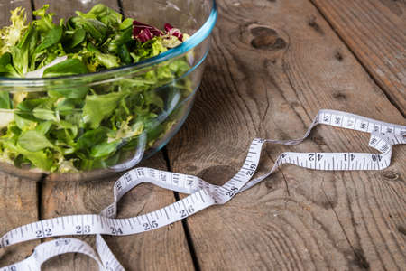 Salad in glass with measuring tape on wood backgroundの写真素材