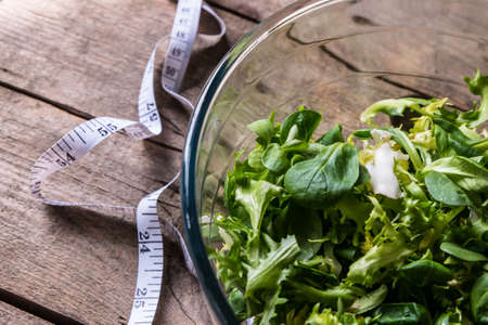 Salad in glass with measuring tape on wood backgroundの写真素材