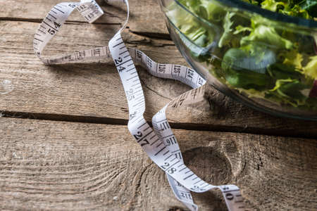 Salad in glass with measuring tape on wood backgroundの写真素材