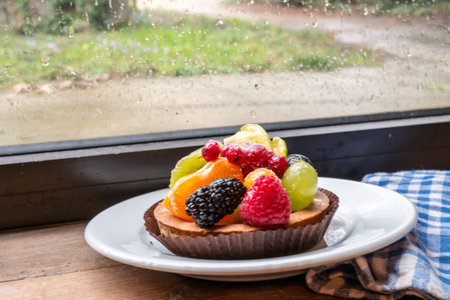 fresh fruit pie tart with kiwi, blueberry, orange and strawberry  in plate close to cotton kitchen...